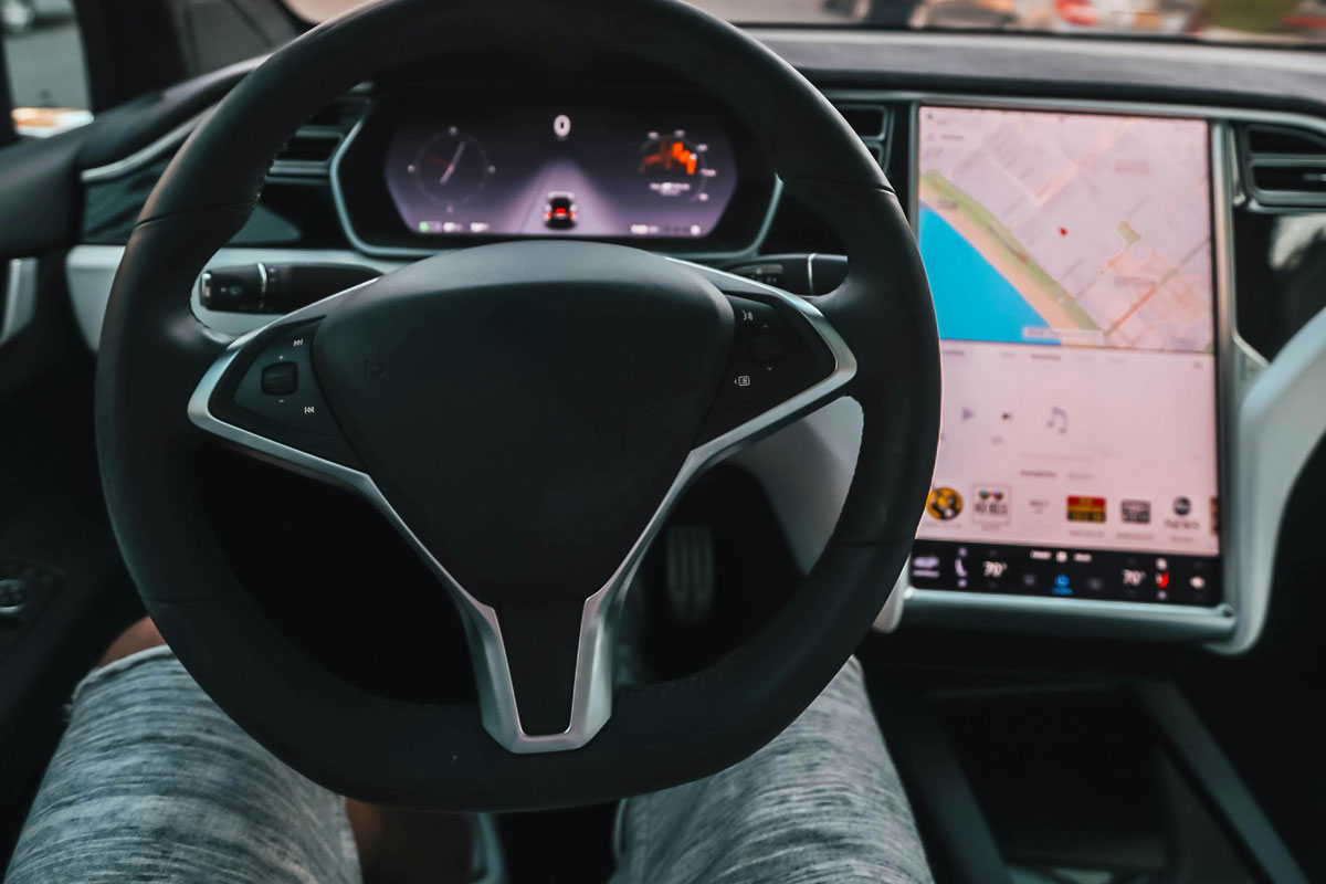 Linguagens de Programação utilizadas em Carros Autônomos homem sentado na direção de carro autonomo