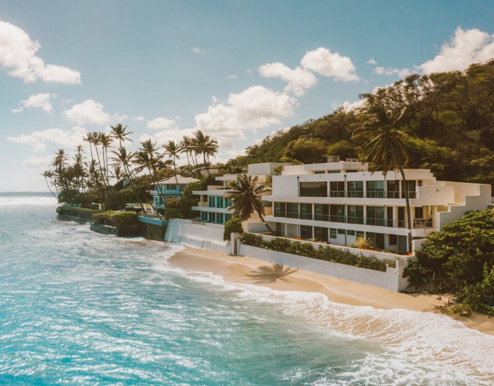IA no mercado imobiliário: avaliando imóveis de luxo na praia Luxurious resort with modern design on a tropical beach, surrounded by turquoise ocean and palm trees.