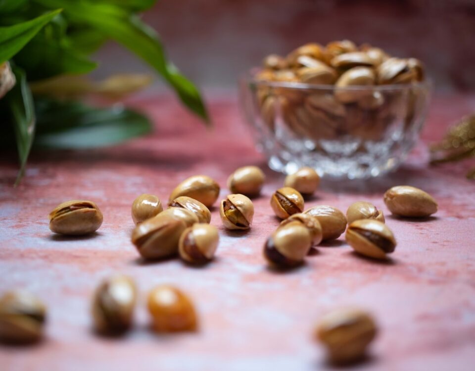 Como a IA está ajudando a calcular os custos do pistache de acordo com o pais de importação a glass bowl filled with nuts on top of a table