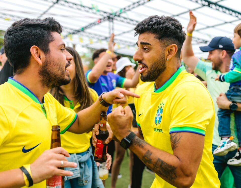 Diferença entre camisa oficial e original: principais dicas Cheerful soccer fans in yellow jerseys celebrating outdoors with excitement and joy.