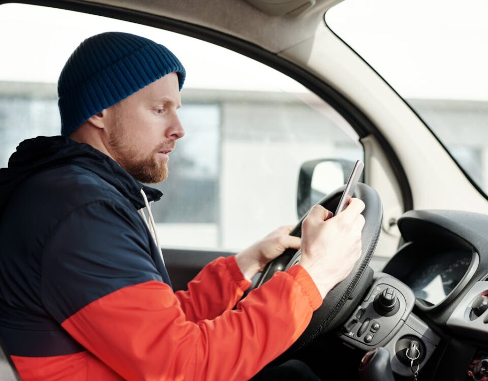 Algoritmos e trânsito: O futuro da CNH Distracted driver uses a smartphone in a car, highlighting road safety concerns.