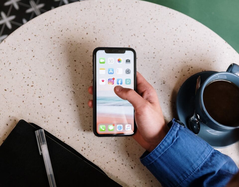 Redes neurais e a previsão de tendências de consumo Person interacts with smartphone and coffee on a terrazzo table, showcasing apps and casual lifestyle.