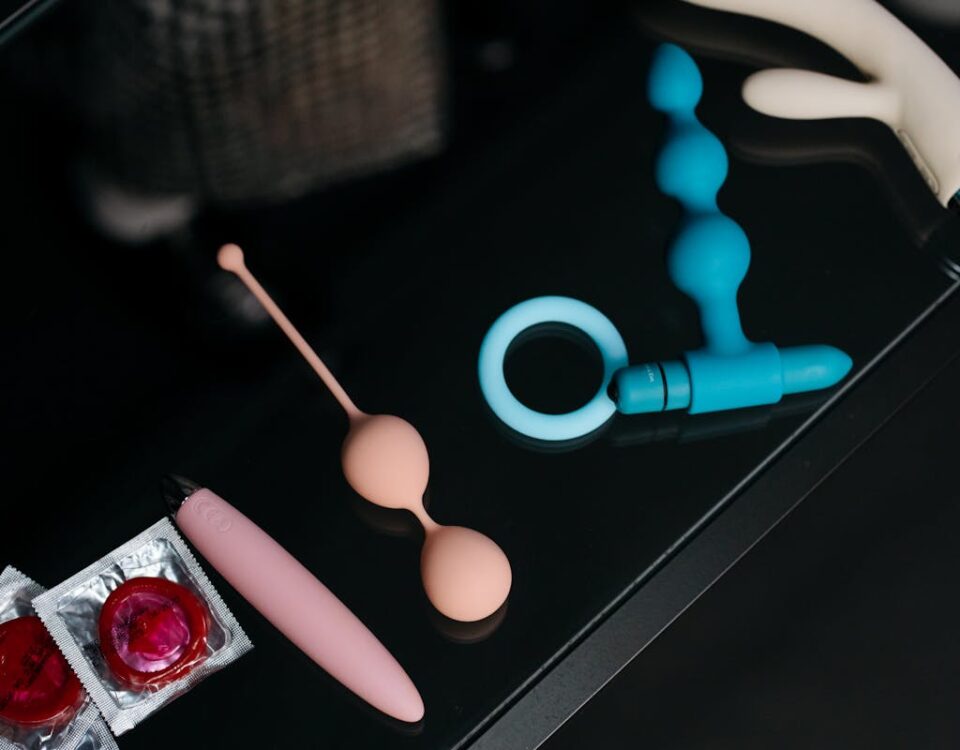 Inteligência artificial no design de produtos adultos A collection of various sex toys and condoms on a reflective tabletop for safe and sensual pleasure.