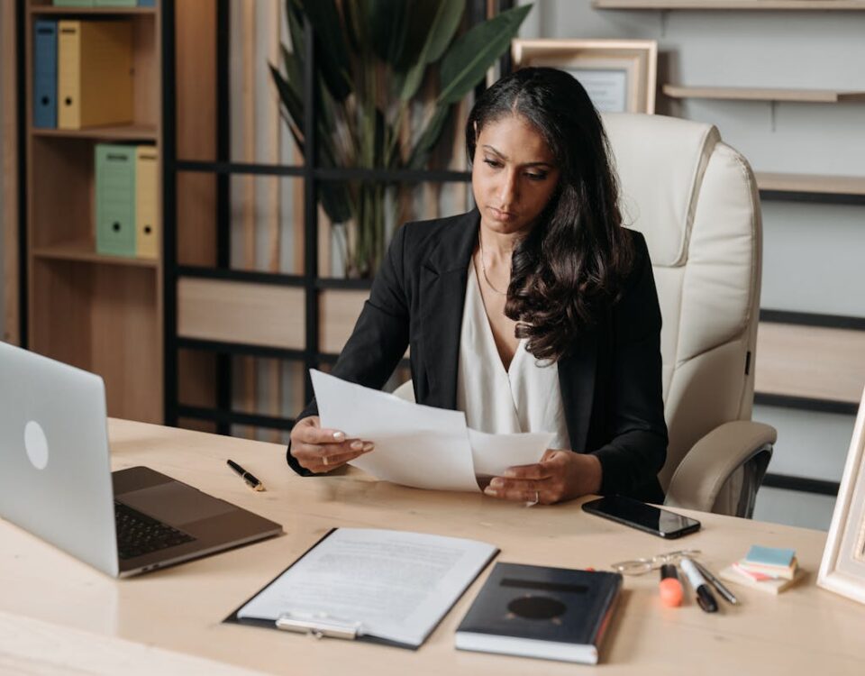 IA nas corretoras de seguros: Como isso funciona? Business woman focused on paperwork at office desk, reviewing documents.