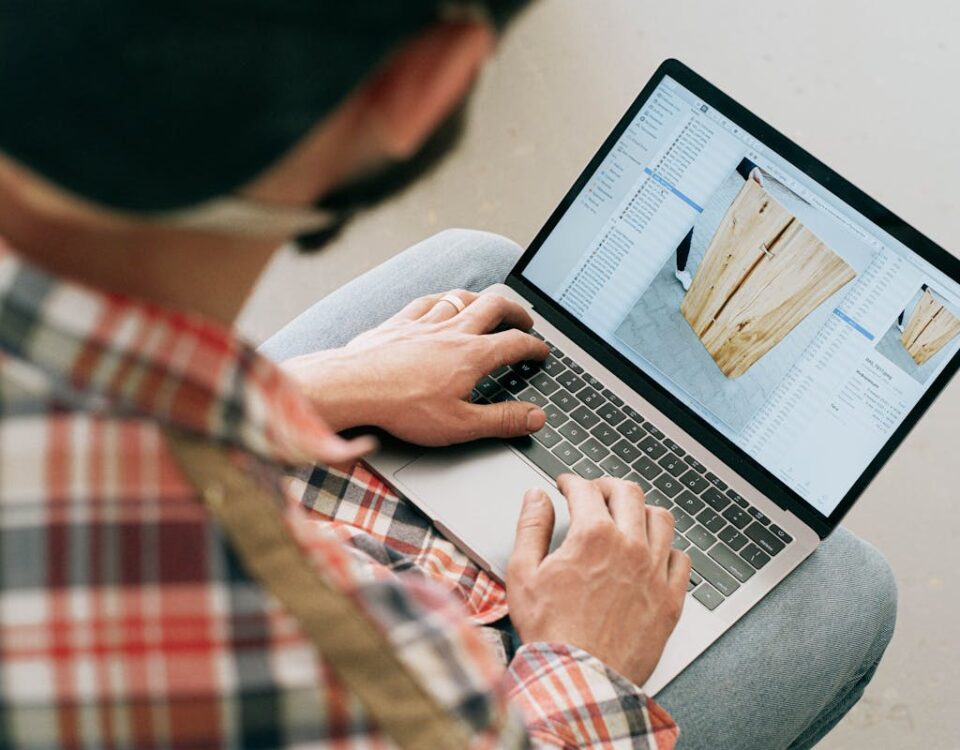 IA no design de móveis: Personalização no segmento de luxo A craftsman uses a laptop to design wooden furniture in a workshop setting.