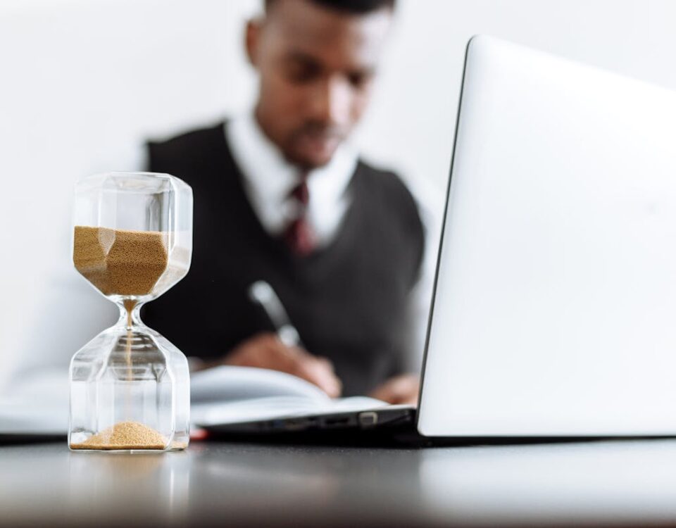 Automação de contratos facilita disputas com planos de saúde Businessman at desk with hourglass indicating time management and daily work routine.