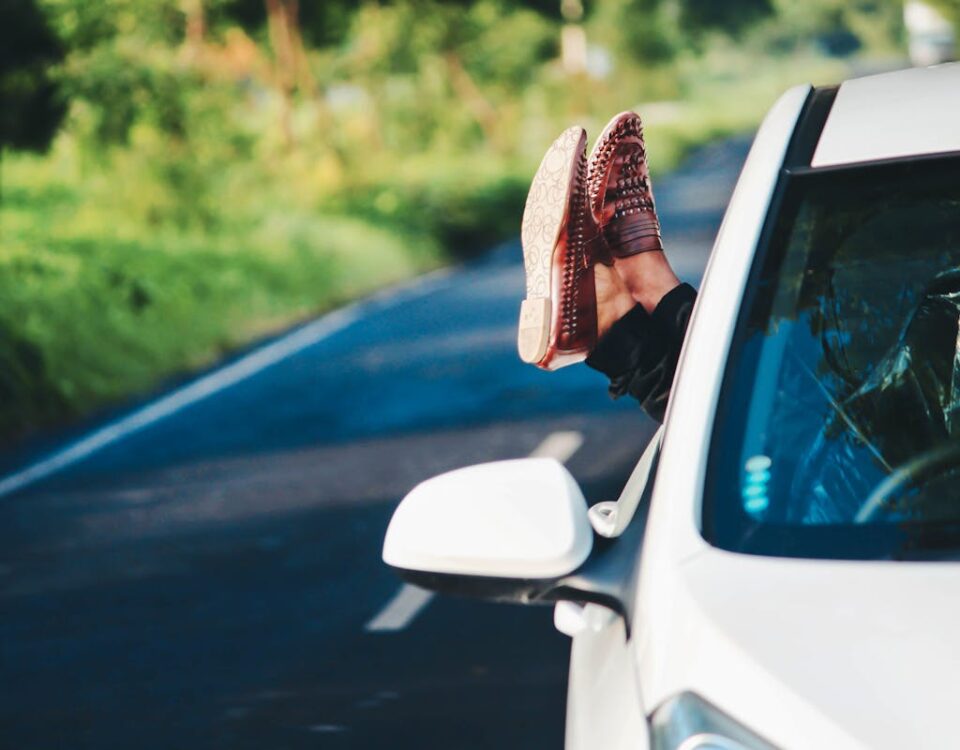 IA no trânsito: como carros estão aprendendo a dirigir Man relaxing in car, scenic road trip in summer. Feet out window, enjoying countryside.