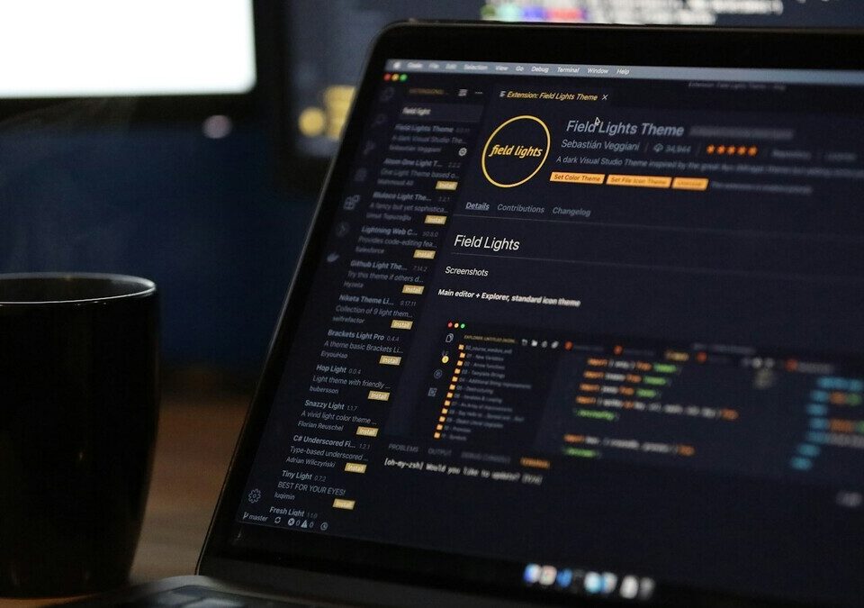 Notebook com código na tela ao lado de uma caneca fumegante