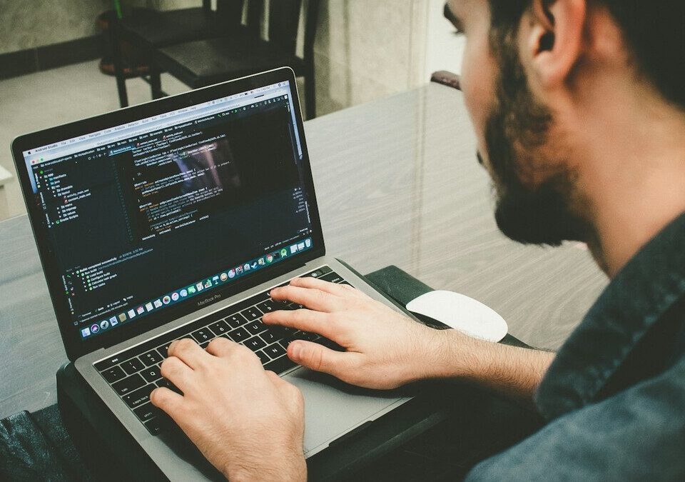 Homem digitando em um notebook com código na tela