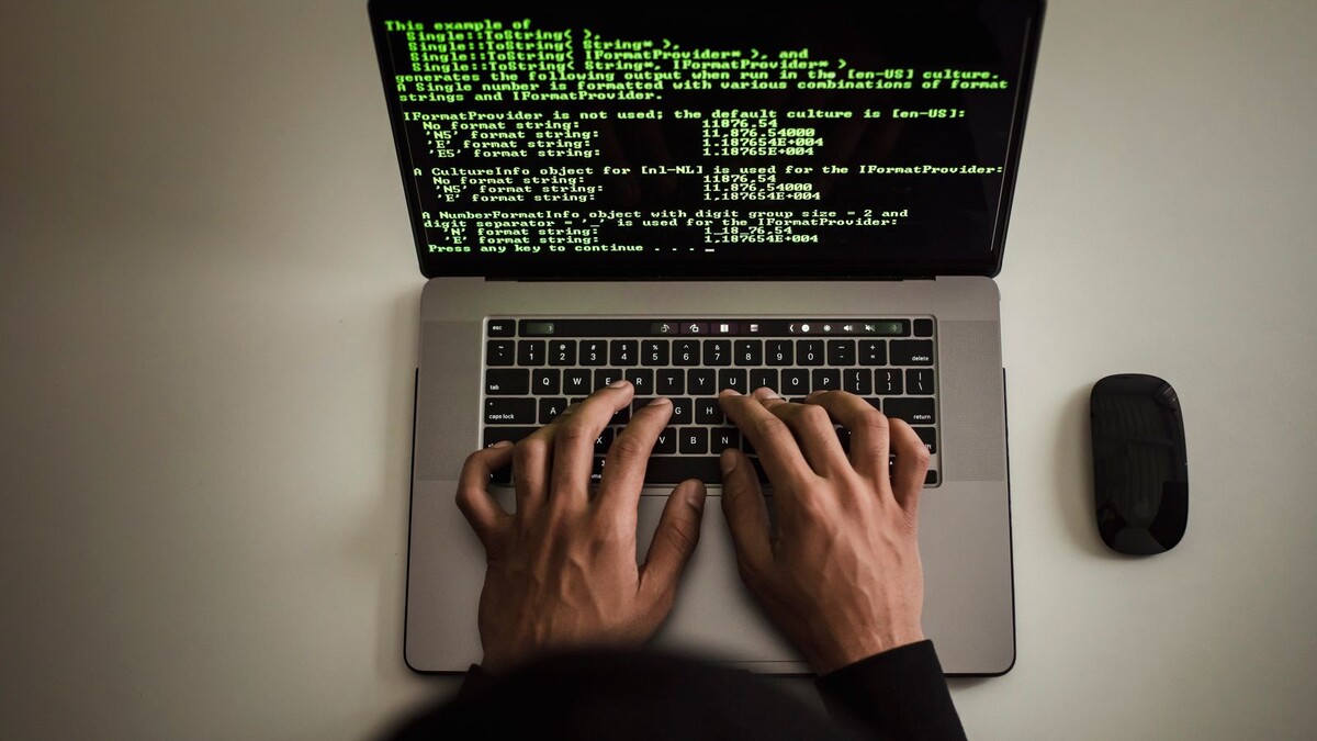 Mãos digitando em um notebook com terminal de texto verde na tela