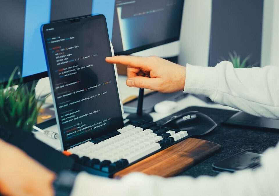 Programador trabalha com código em monitores e notebook