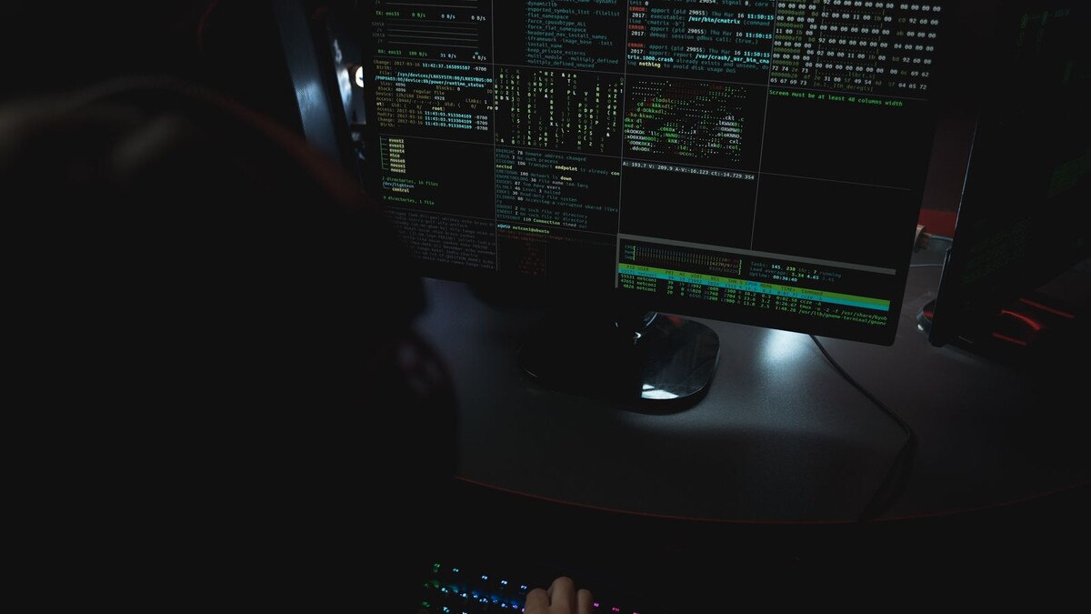 GitHub libera controle de licenças: como preparar os repositórios Pessoa trabalha diante de monitores com código em ambiente de pouca luz